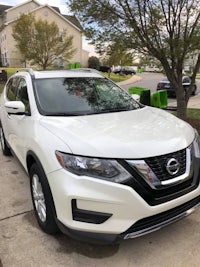 a white nissan rogue parked on the side of the road